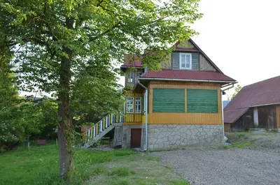 a house with a green door and a tree at Kolorowy Domek in Kasina Wielka