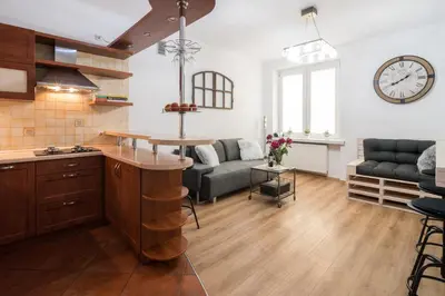 a kitchen and living room with a clock on the wall at THE HEART OF NOWA HUTA - free garage in Kraków