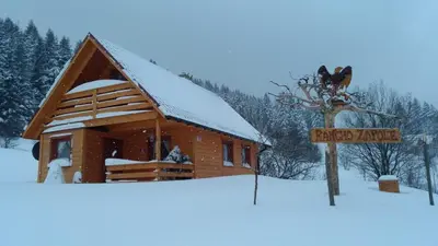 a log cabin with a sign in the snow at Ranczo Zapole in Zasadne