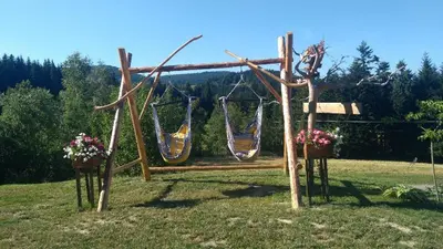 a swing with two hammocks in a field with flowers at Ranczo Zapole in Zasadne