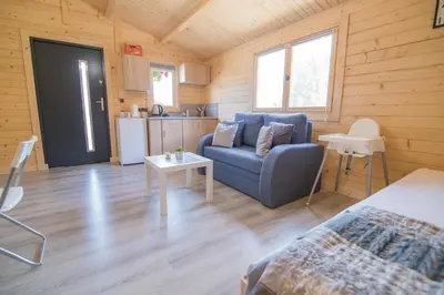a living room with a blue couch and a kitchen at FamilyCamp in Zator