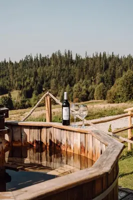 a bottle of wine and two glasses on a wooden table at Domek na uboczu in Klikuszowa