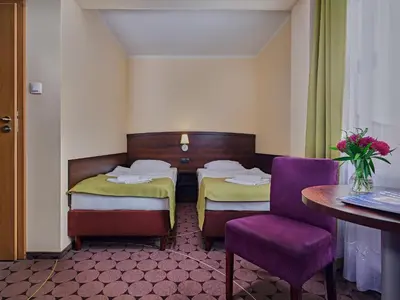 two beds in a room with a table and a chair at Aparthotel Lumen in Kraków