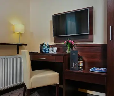 a hotel room with a desk with a tv and a chair at Aparthotel Lumen in Kraków