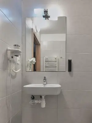 a white bathroom with a sink and a mirror at Aparthotel Lumen in Kraków