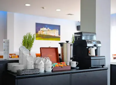 a counter with cups and plates and a coffee maker at Aparthotel Lumen in Kraków