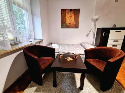 a bedroom with a bed and two chairs and a table at Krakow Centrum Gurgacza Apartments in Kraków