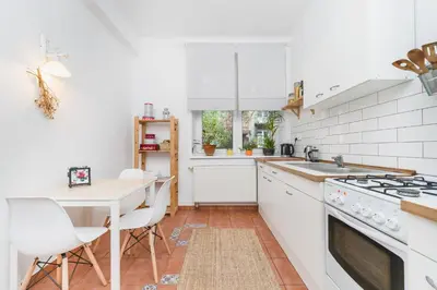 a kitchen with white appliances and a table with chairs at Two separate bedrooms,10 min walk to the city center by Homeclick in Kraków