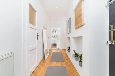 a hallway with white walls and wood floors and rugs at Two separate bedrooms,10 min walk to the city center by Homeclick in Kraków