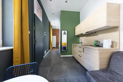 a kitchen with wooden cabinets and green walls at MioMio Apartments in Kraków