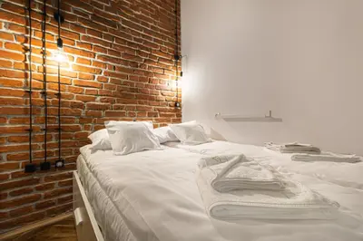 a bed in a room with a brick wall at MioMio Apartments in Kraków