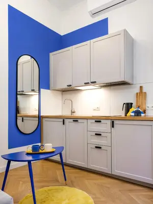 a kitchen with white cabinets and a blue wall at MioMio Apartments in Kraków