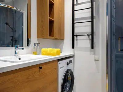 a bathroom with a washing machine under a sink at MioMio Apartments in Kraków