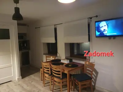 a kitchen with a table and chairs and a tv on the wall at Apartament STUDIO i Apartament ZADOMEK Spytkowice koło ZATORA in Spytkowice