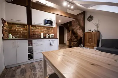 a kitchen with white cabinets and a wooden table at Apartamenty Za Winklem in Kraków