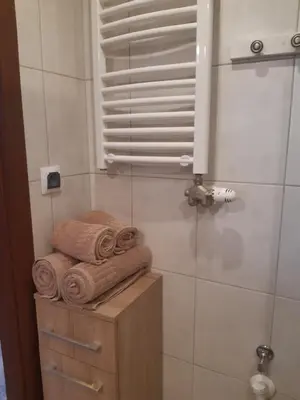 a bathroom with a stack of towels on a shelf at Apartamenty Za Winklem in Kraków