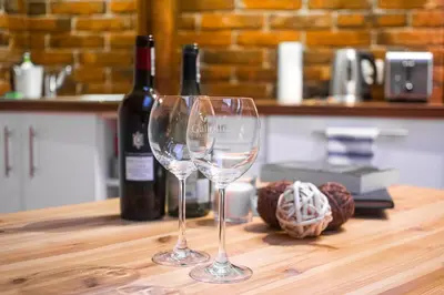 two wine glasses sitting on a table with bottles of wine at Apartamenty Za Winklem in Kraków