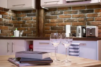 two glasses of wine on a table with a book at Apartamenty Za Winklem in Kraków