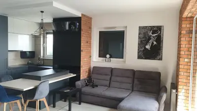 a living room with a couch and a table and a kitchen at Luksusowy apartament z tarasem in Kraków
