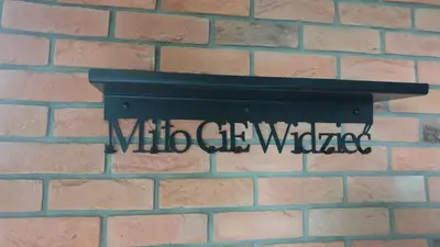 a wall with a black sign on a brick wall at Luksusowy apartament z tarasem in Kraków