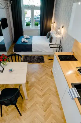 a small room with a bed and a desk and a kitchen at Cracovia Wawel Apartments in Kraków