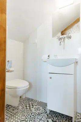 a white bathroom with a toilet and a sink at Pokoje Gościnne Cheval in Kraków