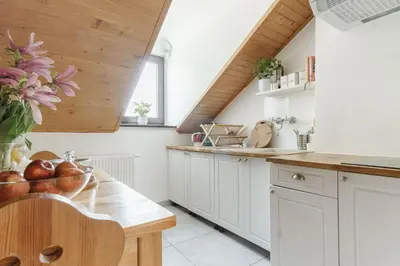 a kitchen with white cabinets and a wooden ceiling at Pokoje Gościnne Cheval in Kraków