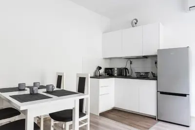 a white kitchen with a table and a refrigerator at Tomasza 20 Apartment 140m2 in Kraków