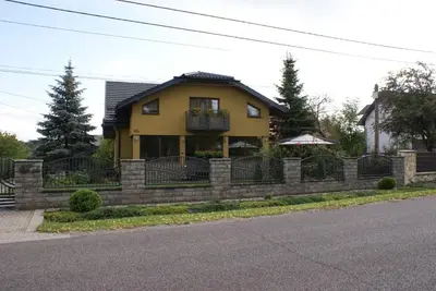 a yellow house with a stone retaining wall at Agrogosia in Czajowice
