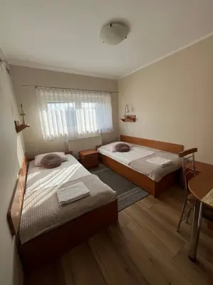 a room with two beds and a table and a desk at Dom Kolping in Kraków