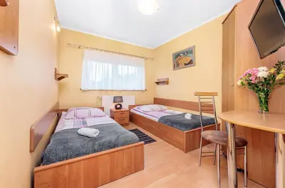 two beds in a room with a table and a desk at Dom Kolping in Kraków