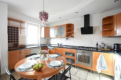 a kitchen with a wooden table and a dining room at Mhost Bronowice in Kraków