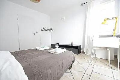 a white bedroom with a bed and a sink at Mhost Bronowice in Kraków