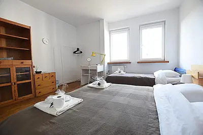 a bedroom with two beds and a dresser and windows at Mhost Bronowice in Kraków