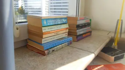 a stack of books sitting on the floor next to a window at Mhost Bronowice in Kraków
