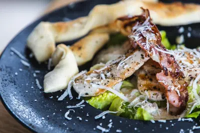 a black plate of food with chicken and broccoli at JJ Sport Concept Hotel in Kraków