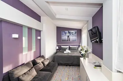 a room with a bed and a couch and a tv at JJ Sport Concept Hotel in Kraków