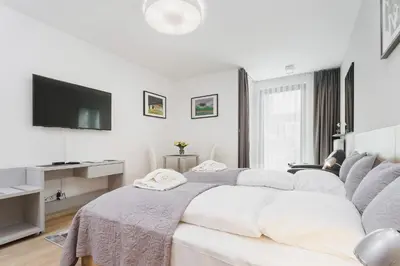 a white bedroom with a bed and a flat screen tv at Apartments Kraków Rajska 3 by Noclegi Renters in Kraków