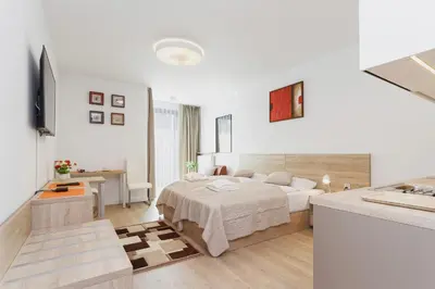 a white bedroom with a bed and a desk at Apartments Kraków Rajska 3 by Noclegi Renters in Kraków
