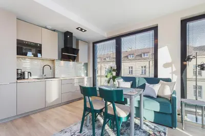 a kitchen and living room with a blue couch and a table at Apartments Kraków Rajska 3 by Noclegi Renters in Kraków