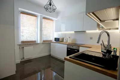 a kitchen with white cabinets and a sink at Apartament Daszyńskiego in Kraków