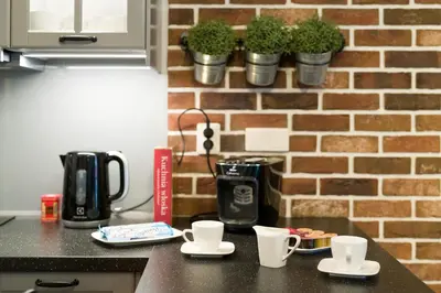 a kitchen counter with two coffee cups and a brick wall at Orange, modern apartment in the city centre in Kraków