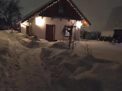 a house covered in snow at night with lights at Na Szlaku - domki do wynajęcia in Rabka