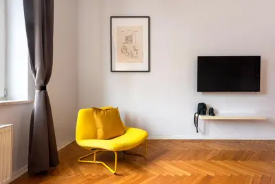 a yellow chair in a room with a television at City Vibes Apartments in Kraków