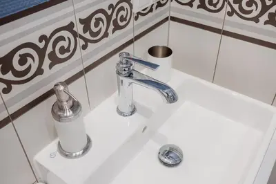 a white bathroom sink with a soap dispenser on it at Exclusive 