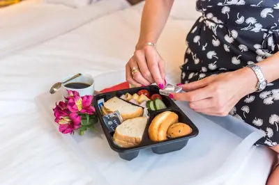 a woman holding a lunch box with bread and vegetables at AirPark Balice in Balice