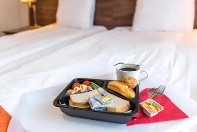 a tray of food on a bed with a cup of coffee at AirPark Balice in Balice
