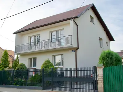 a white house with a black fence at Apartamenty ZORZA in Kraków