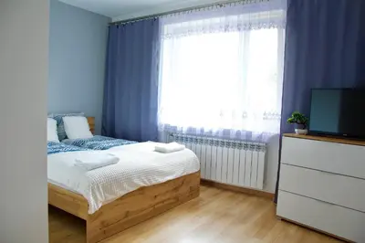 a blue bedroom with a bed and a television at Apartamenty ZORZA in Kraków