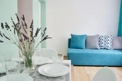 a living room with a table and a blue couch at Apartamenty ZORZA in Kraków